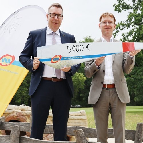 Daniel Peters (rechts) von UKA Cottbus überreicht Peter Albert von der Bürgerstiftung erneut eine Spende über 5.000 Euro für den Wasserspielplatz im Eliaspark.