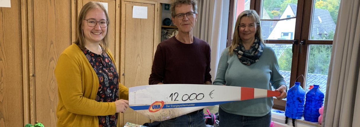Anna Ehrenbrink von UKA (links) überreicht die Spende symbolisch mit den Rotor einer Windenergieanlage an Volker Haas und Sabine Bordihn vom Kinderschutzbund.